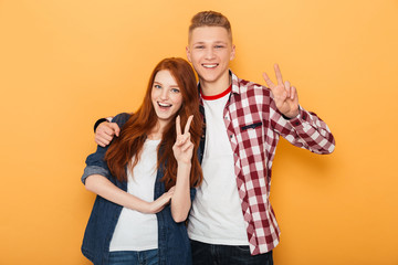 Wall Mural - Portrait of a happy teenage couple showing peace