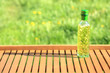 Kwadratowa butelka z olejem rzepakowym z czosnkiem i bazylją na drewnianej tacy.