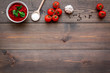 © 9dreamstudio - Ingredients for tomato sauce. Cherry tomatoes, garlic, green basil, black pepper, salt in spoon on dark wooden background top view copy space