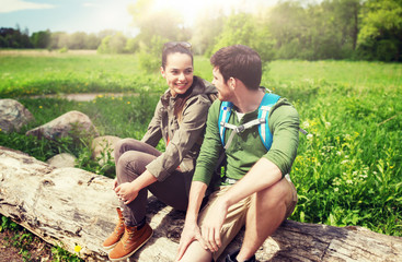 Poster - travel, hiking, backpacking, tourism and people concept - smiling couple with backpacks resting and talking in nature