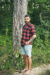 Wall Mural - Bearded hipster in woods. Brutal lumberjack waiting on path. Barefoot guy standing on ground