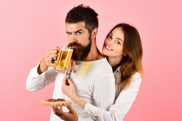 Happy romantic couple eating pizza, drinks beer. Loving couple enjoy yummy pizza. Pretty young girl holds slice yummy pizza and handsome boyfriend holds glass of beer. Couple enjoying pizza together.