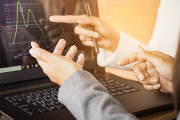 two businesswoman working together on computer laptop with financial graph on screen, teamwork concept