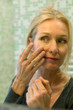 © PhotoAlto - Mature woman scrutinizing her face in bathroom mirror