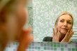 © PhotoAlto - Mature woman scrutinizing her face in bathroom mirror
