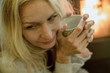 © PhotoAlto - Mature woman relaxing by fire with warm drink