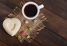 Cup Of Hot Aromat Coffee And A Sesame Dessert In The Shape Of A Heart On An Old Wooden Background.