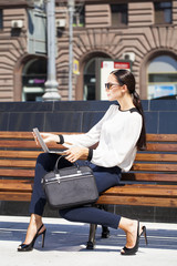 Wall Mural - Young beautiful business woman working on laptop, summer street