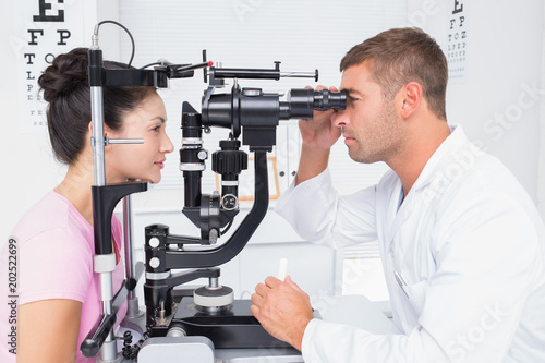 Fotografía Optician examining womans eyes through slit lamp