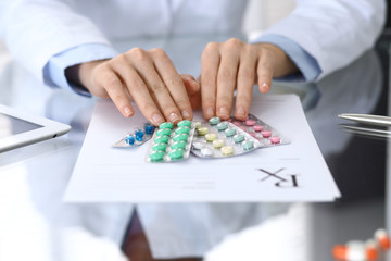 Doctor holding pack of different tablet blisters closeup. Life save service, legal drug store, prescribe medication, blood pressure, disease healing concept