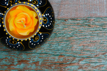 A  Wooden Candle Holder With An Orange Candle