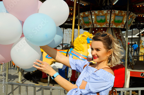 Fotografie, Tablou Beautiful young woman with balloons in the amusement park