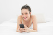 © WavebreakmediaMicro - Happy casual woman with mobile phone in bed