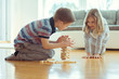 © spass - Two happy siblings playing a game with wooden blocks at home