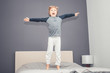 Playful boy with arms outstretched having fun in bedroom.