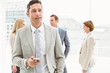 © WavebreakmediaMicro - Businessman text messaging with colleagues in meeting behind