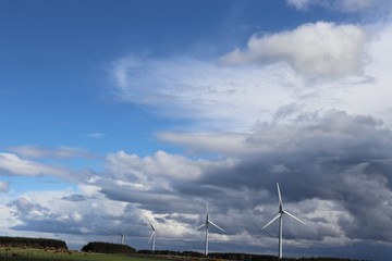 Wind tturbines against blue sky with fluffy white clouds