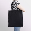 Girl is holding black cotton eco tote bag, design mockup.