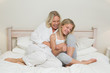 Happy mother tickling daughter in bed