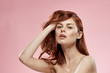 red-haired woman pink background bare shoulders