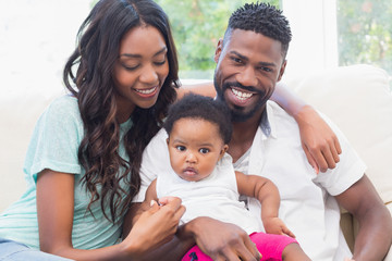 Wall Mural - Happy couple with their baby girl on couch