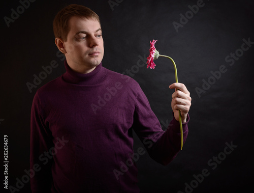 Fotografie, Obraz Young man hold gerbera flower in hand. Selective focus.