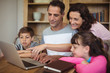 © WavebreakmediaMicro - Parents and kids using laptop on table in study room