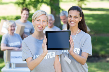 Canvas Print - Happy volunteer friends showing tablet pc screen