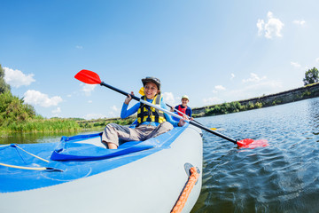 Happy boy kayaking on the river on a sunny day during summer vacation