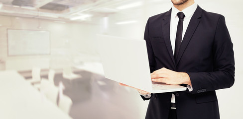 Canvas Print - Mid section of a businessman using laptop against classroom