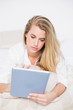 © WavebreakmediaMicro - Focused model using her tablet lying on cosy bed