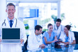 © WavebreakmediaMicro - Doctor showing laptop with colleagues behind