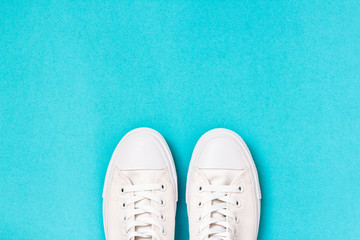 Pair of new white sneakers on blue background. Top view 