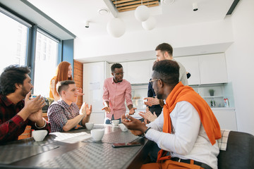 African man with serious face telling amusing anecdotes to co-workers in break time