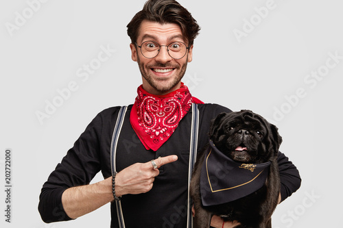 Look At My Lovely Pet Positive Stylish Male Model In Elegant Clothes Indicates At Black Pug