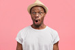 Portrait of stunned African American adult looks with amazed expression, being shocked to have spoiled vacation, poses against pink background. Surprised dark skinned male wears casual clothing