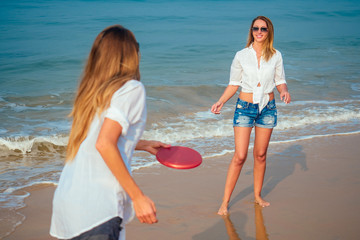 two women on the beach playing with a flying disc