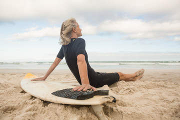 Wall Mural - Side view of senior woman leaning on surfboard