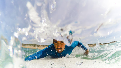 Poster - Front view of a surfer paddling surrounded by water