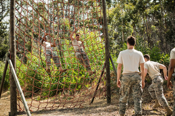 Wall Mural - Military soldiers climbing rope during obstacle course