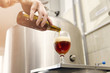 Closeup  man poring glass with red IPA beer in brewery , fermenter in background