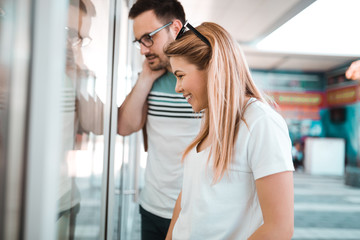 Wall Mural - Boyfriend and girlfriend is watching through shop windows while they are outside