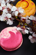 © alexmishchenko - Two unusual beautiful macaron \ macaroon and a branch of a flowering tree. Black matte background. Sweet delicious dessert in the style of minimalism. Flowering cherry, sakura, apple, plum.