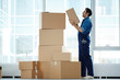 © pressmaster - Young relocation agency staff in workwear going to put box on top of stack while doing his work