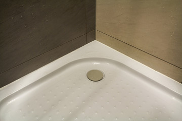 Close-up detail of new modern clean empty white shower cabin with drops of water on nice light beige ceramic tiles on floor and walls. Comfort and hygiene concept.