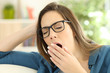 Fatigued woman yawning at home