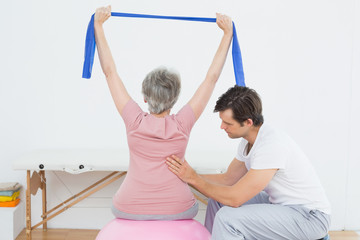 Senior woman on yoga ball with a physical therapist