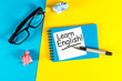 Learn english - note at blue and yellow background with teachers glasses