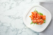 Plate with fresh sliced salmon fillet and arugula on marble background, top view