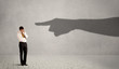 © ra2 studio - Business person looking at huge shadow hand pointing at him concept on background